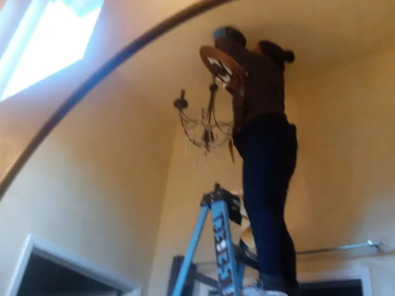 Electrician installing a chandelier in a Latrobe residence